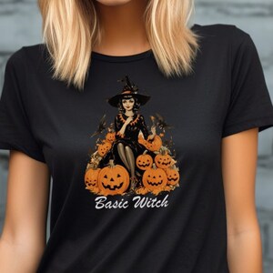 May include: Black t-shirt with a graphic of a witch sitting on a pile of pumpkins. The text "Basic Witch" is printed below the graphic.