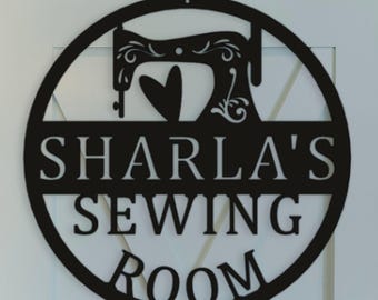 May include: A circular black metal wall sign featuring a silhouette of a vintage sewing machine above a heart shape. The text "SHARLA'S SEWING ROOM" is cut out in the center of the sign, which is mounted on a white paneled door.