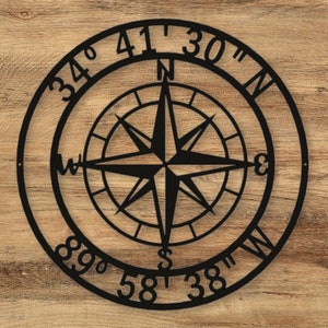 May include: Black metal compass with a star design and the coordinates 34° 41' 30" N 89° 58' 38" W.