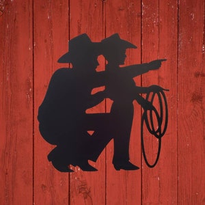 Cowboy and Son Metal Sign is hanging on a wall.