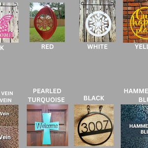 May include: A selection of metal signs in various colors and finishes. The signs feature different designs, including a butterfly, a snowflake, a circle with the text "Our happy place", and a cross with the word "Welcome". The signs are available in pink, red, white, yellow, copper vein, silver vein, pearled turquoise, black, and hammertone blue.