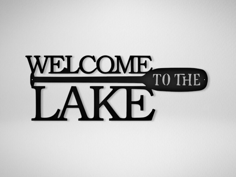 May include: Black metal sign with the words "Welcome to the Lake" and a silhouette of a paddle.