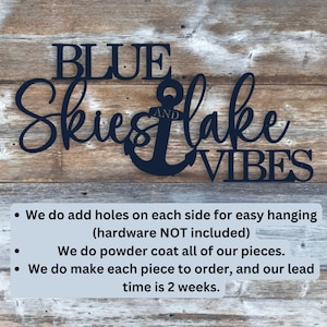 May include: Black metal wall art with the words "BLUE SKIES AND LAKE VIBES" and an anchor. The text is in a cursive font. The art is on a wooden background.