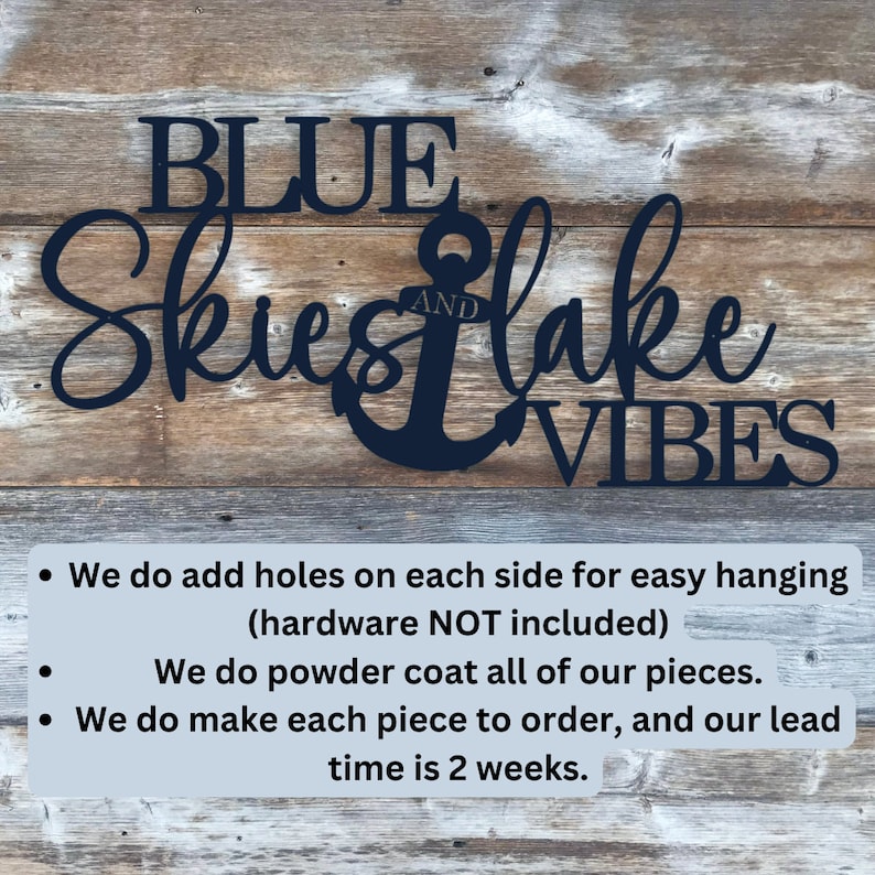 May include: Black metal wall art with the words "BLUE SKIES AND LAKE VIBES" and an anchor. The text is in a cursive font. The art is on a wooden background.