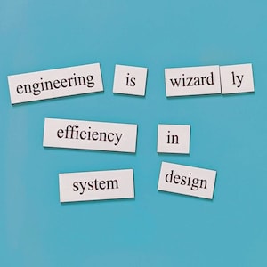 May include: White paper squares with the words "engineering", "is", "wizard", "ly", "efficiency", "in", "system", and "design" on a blue background.