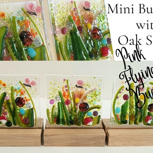 May include: Three small glass tiles with colorful images of flying bugs and flowers on oak stands. The tiles are titled "Pink Flying Bugs" and "Mini Bug Tiles with Oak Stands".