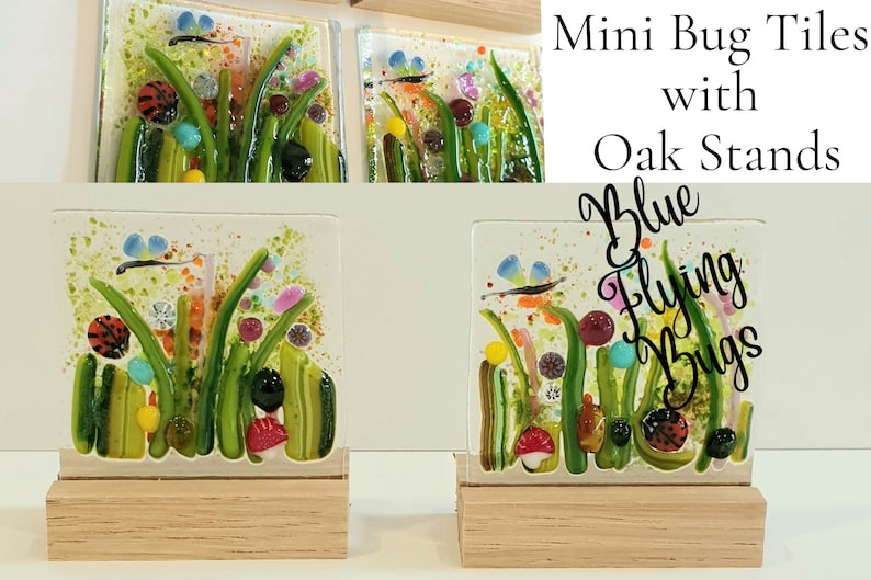 May include: Two small glass tiles with a colorful, abstract design of green grass, flowers, and blue flying bugs. The tiles are on wooden stands. The text "Blue Flying Bugs" is written on the image.