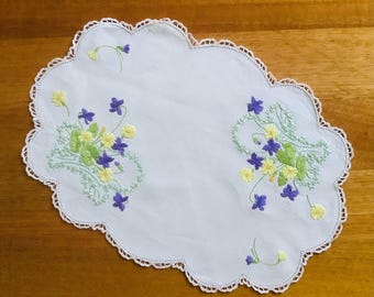 Tapete rectangular bordado a mano con flores moradas y amarillas.