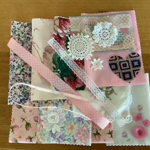 May include: Assortment of pink and white fabric scraps, lace, ribbon, and crocheted doilies. The fabric scraps feature floral patterns and polka dots.
