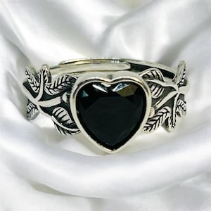 May include: A silver ring featuring a black heart-shaped stone and leaf accents.