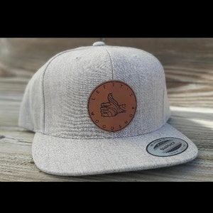 May include: Gray baseball cap with a brown leather patch that says "Lefty's Woodshop" with a thumbs up graphic.
