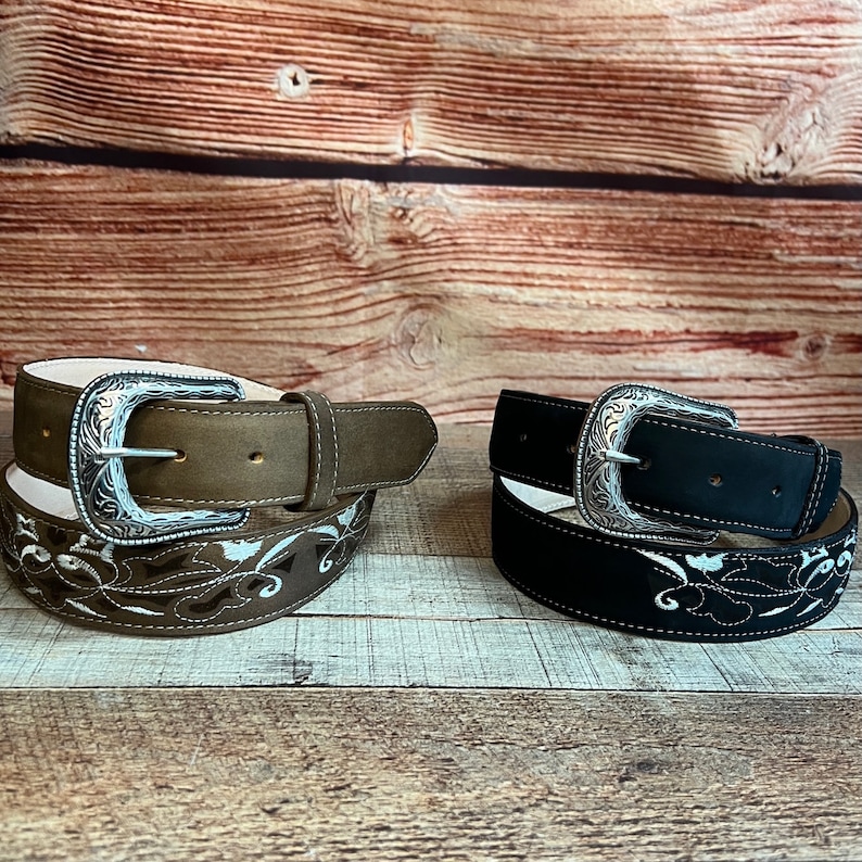 May include: Two leather belts with silver buckles and embroidered floral designs. One belt is brown and the other is black.