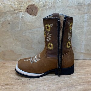 May include: Brown leather children's boots with a side zipper and sunflower embroidery.