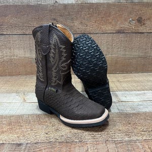 May include: Brown leather cowboy boots with a zipper on the side and a decorative stitch pattern. The boots have a rubber sole.