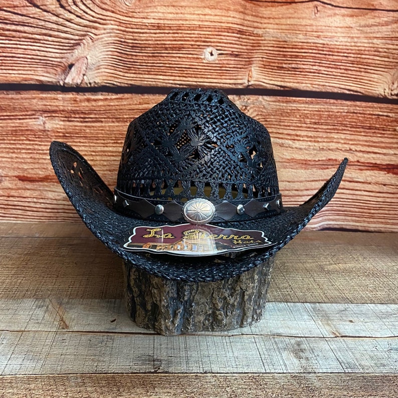 May include: Black cowboy hat with a woven straw design and a brown leather band with silver studs. The hat has a silver concho and a label that reads "La Sierra Hats".