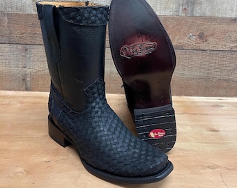 Könnte beinhalten: Schwarze Cowboy-Stiefel aus Leder mit einem gewebten Design an Fuß und Schaft. Die Stiefel haben eine eckige Spitze und einen gestapelten Absatz. Ein Stiefel steht aufrecht, der andere ist umgedreht und zeigt die Sohle.