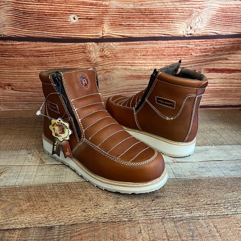 May include: A pair of brown leather ankle boots with white soles and a zipper on the side. The boots have a stitched design and the text "RICO BOOTS" is visible on one boot.