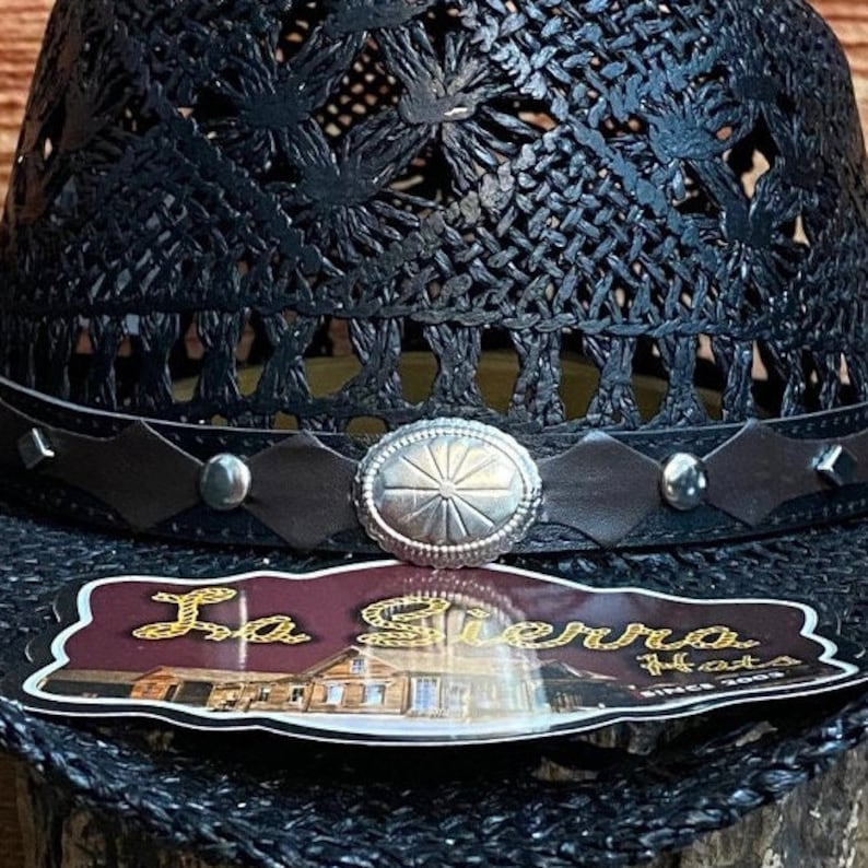 May include: Black woven straw hat with a brown leather band and a silver concho. The hat has a label that says "La Sierra Hats Since 2003".