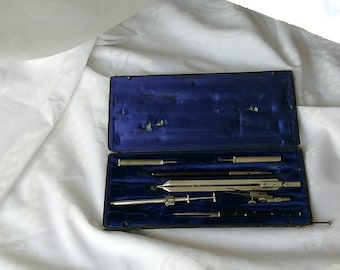 Könnte beinhalten: Ein Vintage-Zeichensatz in einem blau samtenen Etui. Das Set enthält einen Zirkel, einen Teiler, einen Bleistift und ein Lineal.