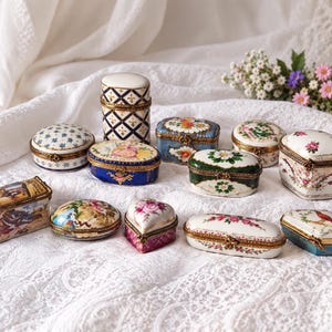 Puede incluir: Una colección de doce pequeñas cajas de porcelana para baratijas con diversas formas, incluyendo diseños ovalados, rectangulares y en forma de corazón. Cada caja está decorada con intrincados motivos florales, bisagras de metal dorado y pinturas.