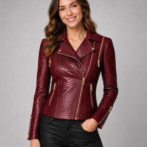 May include: A deep burgundy moto jacket featuring a textured snakeskin pattern, an asymmetrical gold-tone zipper closure, notched lapels, and multiple gold-tone zippered pockets and sleeve cuffs, paired with black pants.