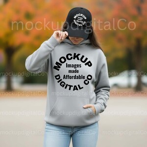 May include: A person wearing a gray hoodie and a black baseball cap. The hoodie has a large circular graphic with the text "MOCKUP Images made Affordable DIGITAL CO". The cap also has text.