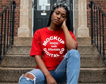 May include: A woman wearing a red t-shirt with the text "MOCKUP Images made Affordable DIGITAL CO" in white. She is sitting on a set of concrete steps.
