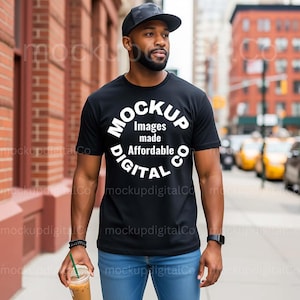 May include: Black t-shirt with the text "MOCKUP Images made Affordable DIGITAL CO" in a circular design. The person is wearing a black cap and blue jeans, holding a beverage with a straw.