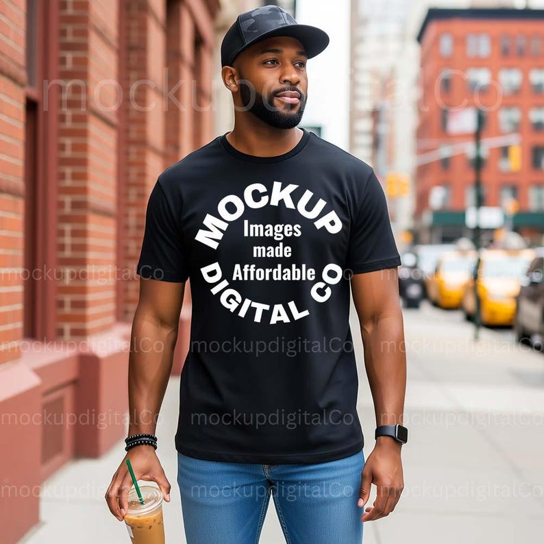 May include: Black t-shirt with the text "MOCKUP Images made Affordable DIGITAL CO" in a circular design. The person is wearing a black cap and blue jeans, holding a beverage with a straw.