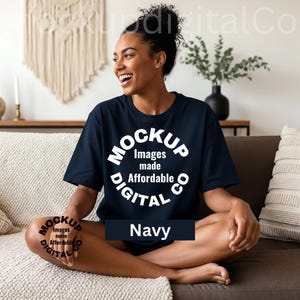 May include: Navy blue t-shirt with a white circular logo that reads "Mockup Digital Co" and "Images made Affordable". The word "Navy" is displayed in a dark blue rectangle. The person is sitting on a brown couch.