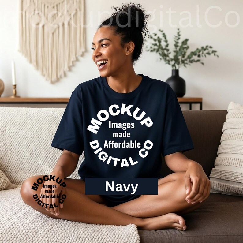 May include: Navy blue t-shirt with a white circular logo that reads "Mockup Digital Co" and "Images made Affordable". The word "Navy" is displayed in a dark blue rectangle. The person is sitting on a brown couch.