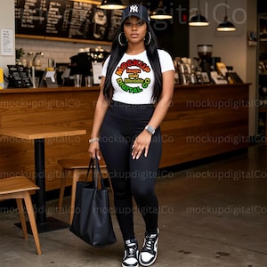 May include: A woman wearing a white t-shirt with a colorful circle graphic that says "Mockup Images Made Affordable Digital Co." She is wearing black leggings, a black baseball cap, and black sneakers. She is holding a black tote bag.