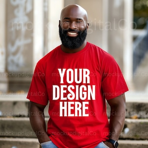 Puede incluir: Una camiseta roja con el texto blanco "YOUR DESIGN HERE". La persona que lleva la camiseta está sonriendo y tiene barba negra. El fondo es un entorno exterior borroso.