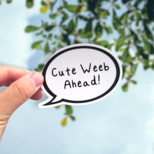 May include: A white speech bubble sticker with a black outline. The sticker says "Cute Weeb Ahead!" in black handwritten text.