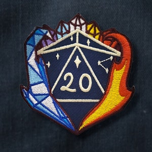 Op de afbeelding: Een blauwe 20-zijdige dobbelsteen met witte cijfers en sterren, omringd door een blauw en wit kristalontwerp aan de linkerkant en een geel en oranje vlamontwerp aan de rechterkant.