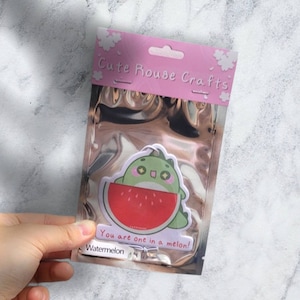 May include: A pink and white packaging bag with a green and red cartoon watermelon character. The bag has the text "Cute Rouse Crafts" and "You are one in a melon!" printed on it. The bag is labeled "Watermelon".