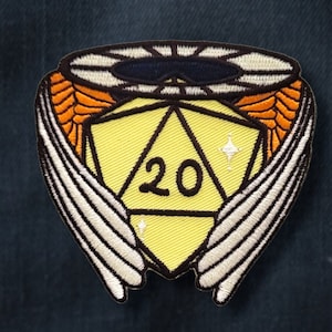 Puede incluir: Un dado amarillo de 20 caras con alas blancas y un halo. El dado está rodeado por un halo negro con acentos blancos.