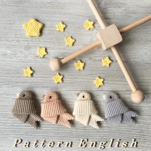 May include: A wooden mobile with four crocheted birds in brown, peach, cream, and gray. The mobile also features yellow crocheted stars.