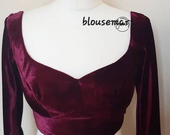 May include: A maroon velvet blouse with long sleeves and a scoop neckline. The blouse has a fitted bodice and a cropped length. The text "blousemygift" is visible on the image.