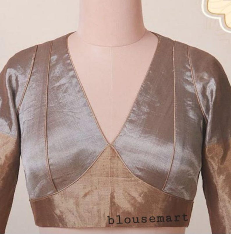 Puede incluir: Una blusa brillante de manga larga en tonos topo y bronce, con un escote en V profundo. La blusa tiene un corte entallado con un panel contrastante en la cintura y el texto "blousemart" en la parte inferior.