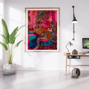 May include: A framed art print depicting a tiger in sunglasses at a bar, set in a vibrant, tropical scene with pink and teal hues. The artwork is in a wooden frame and is displayed in a contemporary interior setting.