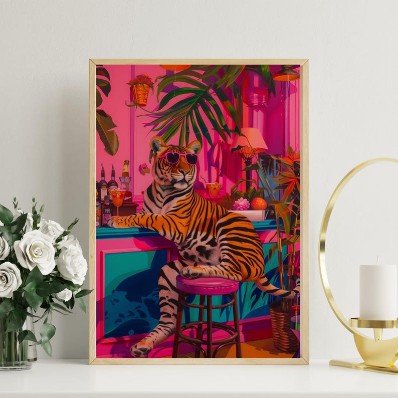May include: A framed art print depicting a tiger in sunglasses at a bar. The tiger has orange and black stripes, seated on a pink stool. The bar is teal and pink, with tropical plants and a pink wall in the background.