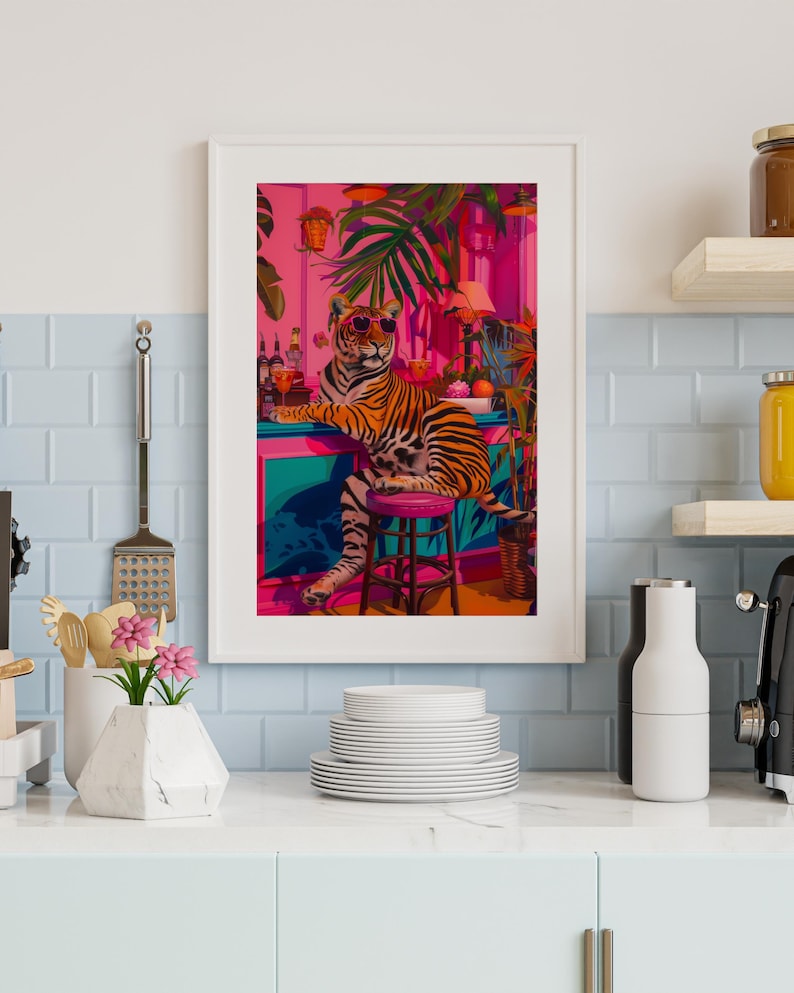 May include: Framed art print depicting a tiger in sunglasses at a bar with a tropical theme. The artwork uses vibrant colours, including pink, teal, and orange, and is surrounded by lush greenery.