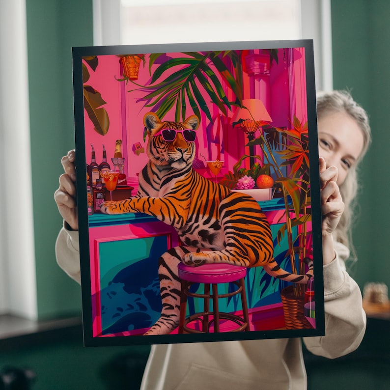 May include: A framed art print depicting a tiger in sunglasses at a bar. The tiger has orange and black stripes, seated on a pink stool. The bar is set in a colourful environment with tropical plants. The colour scheme is pink and teal.