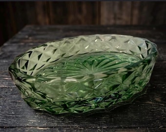 May include: An oval-shaped green glass bowl featuring a textured diamond pattern on the exterior walls and a radiating sunburst design embossed on the interior base. The glass is translucent with a deep emerald hue and polished edges.