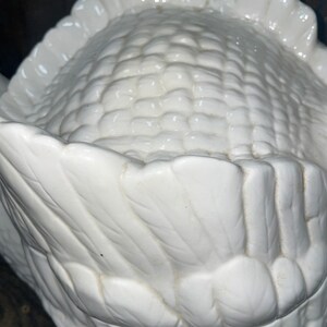 May include: White ceramic corn on the cob serving dish. The dish is shaped like an ear of corn with detailed husks.