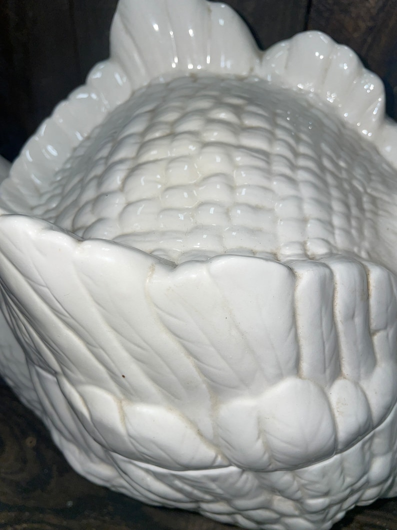 May include: White ceramic corn on the cob serving dish. The dish is shaped like an ear of corn with detailed husks.
