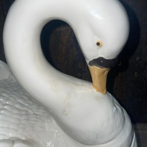 May include: White ceramic swan figurine with a detailed beak and eye. The swan's neck is curved into a heart shape.