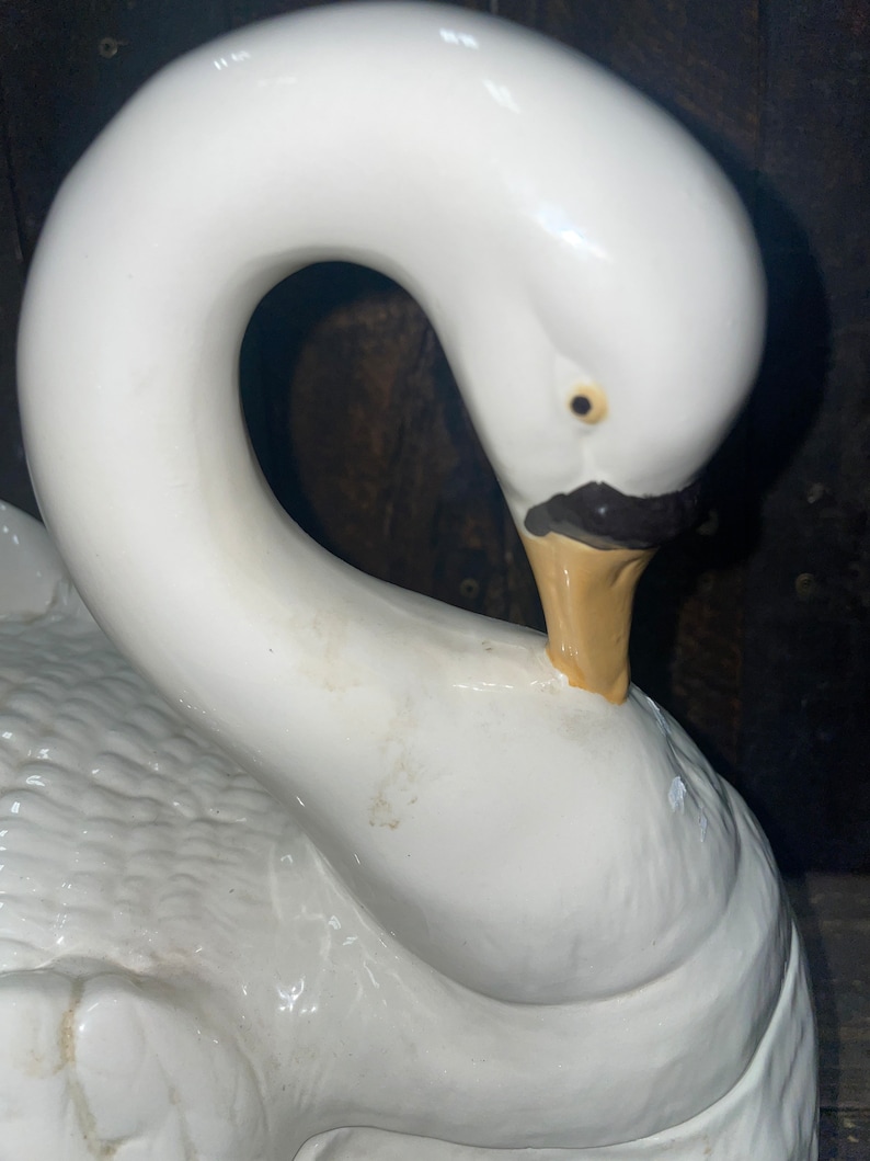 May include: White ceramic swan figurine with a detailed beak and eye. The swan's neck is curved into a heart shape.