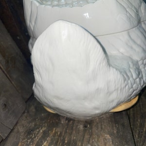 May include: White ceramic goose shaped cookie jar with a textured surface. The lid is open and the inside of the jar is visible.